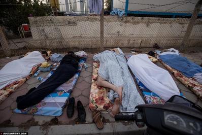 مردانی که در خیابانی بیرون از محوطه شلوغ کلیسای عنکاوه خوابیده اند. شرایط دشوار است، دمای هوا در طول روز به 48 درجه نیز می رسد. 